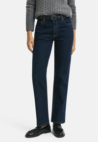 Mörkblå denimjeans med rak passform, med en klassisk femficksdesign och dekorativt sömnad. Matchas med en grå kabelstickad tröja.