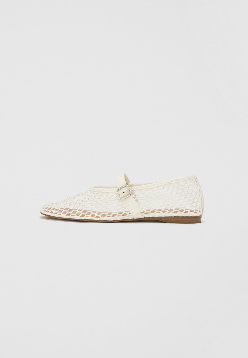 Ivory mesh flat shoe with a rounded toe, featuring a decorative strap with a buckle and a textured sole.