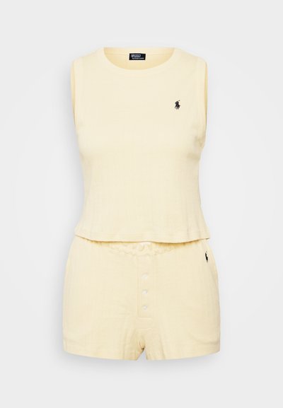 Světle žlutý top bez rukávů s žebrovanou texturou, kombinovaný s odpovídajícími šortkami se zapínáním na knoflík a elastickým pasem, s akcentem loga.
