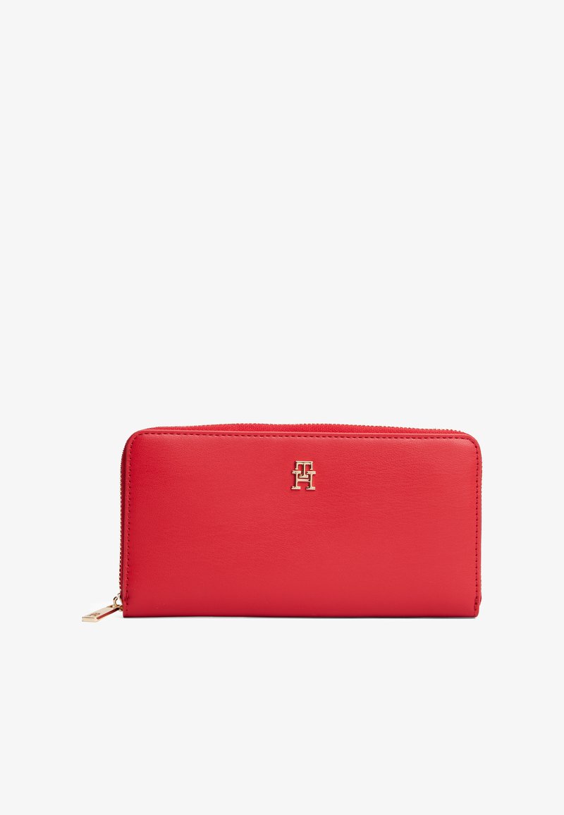 Portefeuille en cuir rouge avec zip tout autour, logo doré centré à l'avant et tirette dorée sur le côté gauche.