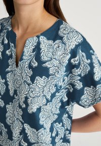 Teal top met een wit bloemachtig paisleypatroon, korte mouwen, V-hals, van zachte stof, met ingewikkelde ontwerpen en een losse pasvorm.