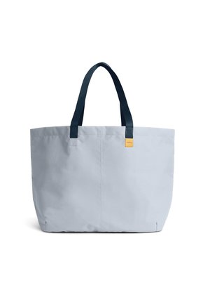 Borsa tote grigio chiaro con manici blu scuro e una piccola etichetta gialla. Presenta una texture morbida in tessuto e una forma rettangolare.