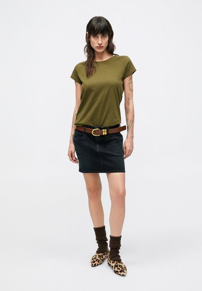 Haut vert olive à manches courtes, mini-jupe en jean foncé, ceinture marron avec boucle dorée, chaussettes côtelées marron, chaussures pointues à imprimé léopard.