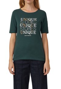 Donkergroene katoenen T-shirt met korte mouwen, met een centrale afbeelding van gestileerde tekst in verschillende kleuren: "UNIEKE VERHALEN" en "CREËER JE EIGEN."