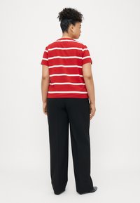 Κόκκινο και λευκό ριγέ κοντομάνικο πουκάμισο, πίσω όψη, συνδυασμένο με μαύρο παντελόνι φαρδύ. Λεπτή υφή, απλή εφαρμογή και απλός σχεδιασμός.