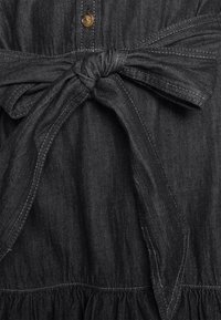 Dark denim dress with a button-down front, knotted waist tie, and gathered fabric at the hem. Soft texture and subtle sheen.