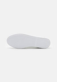 Semelle de chaussure en caoutchouc blanc avec un motif de grip texturé, présentant un design épuré et une forme arrondie. Pas de marquages ou d'accents visibles.