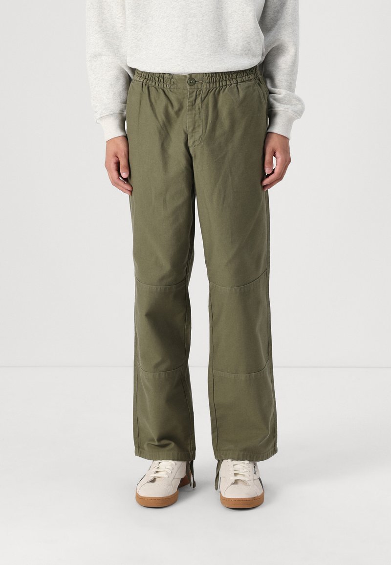 Pantalones de pierna ancha en verde olivo, confeccionados con un tejido ligero, que cuentan con una cinturilla elástica con botón y bolsillos laterales.