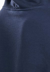 Gros plan sur un tissu bleu marine à la texture douce avec des coutures visibles sur le bord supérieur.
