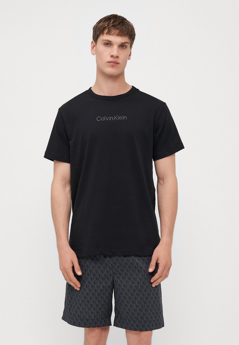 Fekete pamut póló kerek nyakkivágással és rövid ujjakkal, az elején egy diszkrét szürke "Calvin Klein" logóval.