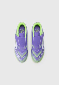 Scarpe sportive viola con accenti verdi, caratterizzate da un design testurizzato, una fascia con chiusura a strappo e un motivo a chevron sulla superficie superiore.
