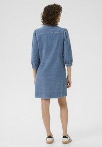 Denim-mekko, vaaleansininen väri, puffatut hihat, napitettava halkio takana, polvipituinen, joustavilla resoreilla, tekstuuri kangasta.