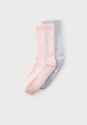 Une paire de chaussettes courtes, douces et côtelées, une rose pâle et une gris clair, présentée sur un fond uni.