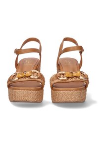Sandalias de plataforma en tono marrón con suela de paja trenzada, correas de cuero y detalle de hebilla en tono dorado. Textura suave y diseño de punta abierta.