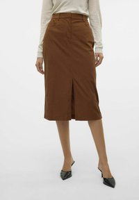 Ruda iki kelių ilgio sijonas su priekinėmis skeltimis, pagamintas iš tekstūruotos medžiagos. Derinamas su juodais smailiais mules. Minimalistinio dizaino, pritaikytas fitas.