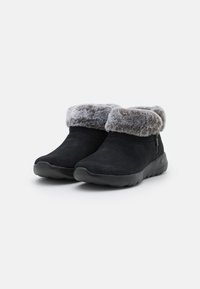 Stivali alla caviglia in suede nero con bordo in pelliccia sintetica grigia e chiusura con zip laterale, dotati di suola in gomma per una migliore aderenza e comfort.