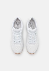 White athletic shoes with perforated upper, lace-up design, and Memory Foam insole. Rubber outsole with a tan accent.