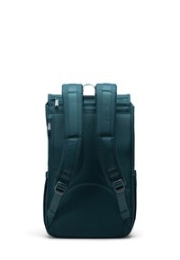 Mörk teal ryggsäck med två justerbara remmar, ett handtag på toppen och ett blixtlås-fack. Slät textur med rektangulär form och minimalistisk design.