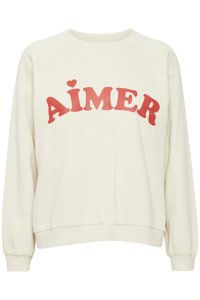 Cream-colored sweatshirt with long raglan sleeves and ribbed cuffs. Features bold red text "AIMER" and a small heart accent above the "I".