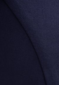 Ciemnoniebieska tkanina o gładkiej teksturze i skośnych przeszyciach, prezentująca prosty, nowoczesny design.