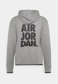 Sweat à capuche gris avec le texte noir "AIR JORDAN" empilé au dos et un petit logo Jumpman en bas à droite du texte.