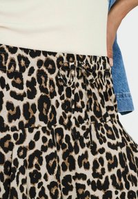 Luipaardprint rok met een trekkoord in de taille, met een beige achtergrond en zwart-bruin vlekken, gemaakt van lichtgewicht stof.