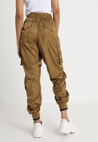 Knielange, gestructureerde cargobroek in khaki kleur met een elastische tailleband en zwarte manchetaccenten; voorzien van twee zijzakken.