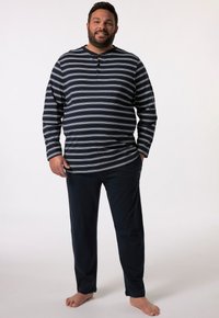 Camisa de manga larga a rayas en azul marino y blanco con cuello redondo y tres botones, combinada con pantalones de un azul marino oscuro. Ajuste casual, tejido suave.