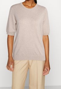 Beige korte mouwen sweater van zachte gebreide stof, met een klassieke ronde hals en geribbelde manchetten, gecombineerd met lichtbeige wijde broek.