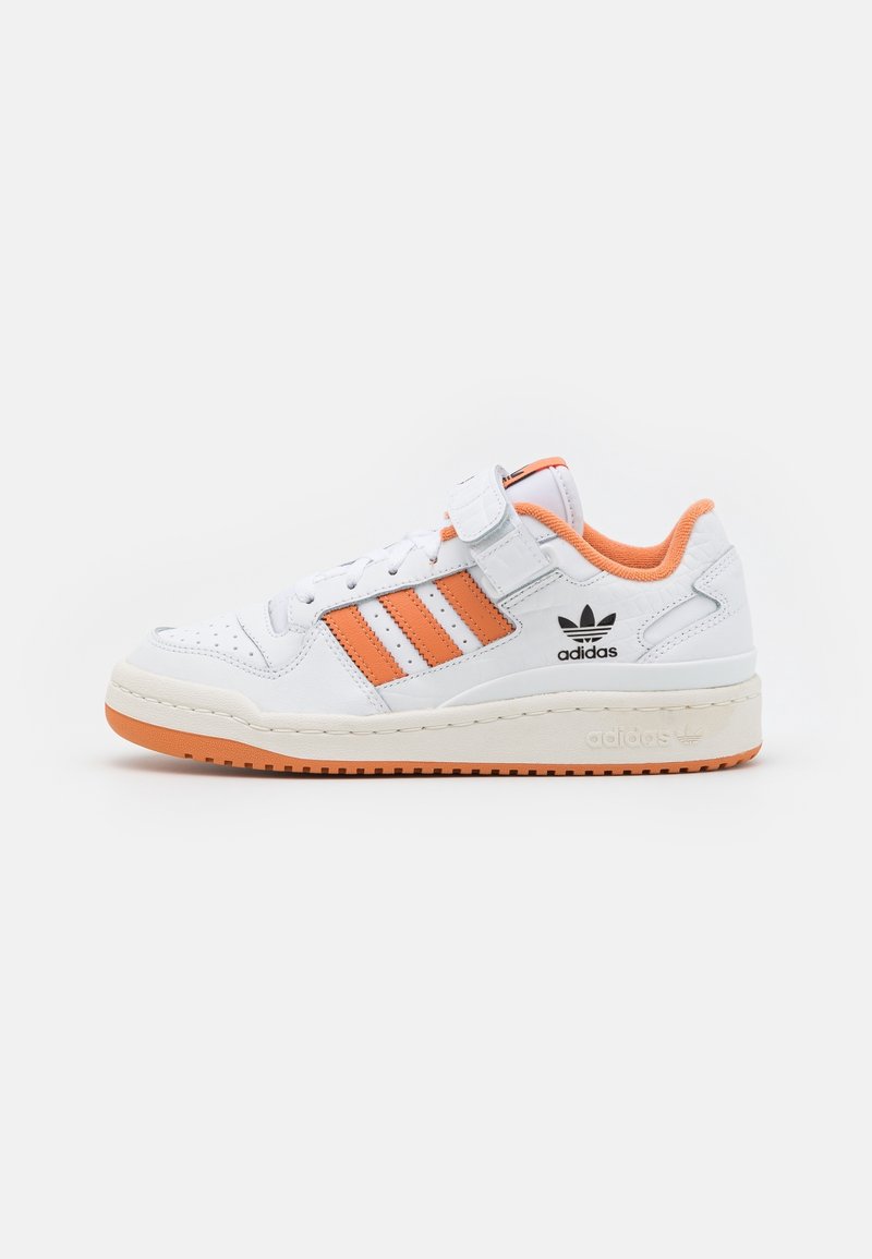 Sneaker en cuir blanc avec des accents orange, présentant trois bandes oranges, une sangle en velcro et une semelle en caoutchouc texturée.