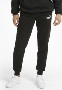 Pantalones jogger de forro polar negros con un ajuste ceñido, cintura elástica y puños acanalados. Logo blanco de Puma exhibido en el muslo izquierdo.