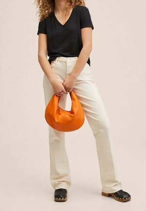 Czarna koszulka z dekoltem w kształcie litery V, kremowe spodnie o prostych nogawkach, czarne drewniane klapki oraz jaskrawopomarańczowa skórzana torebka.