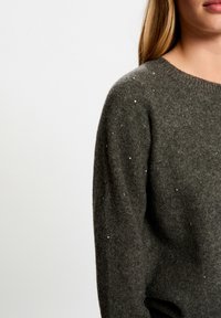 Suéter de lana gris oscuro con cuello redondo, que presenta una superficie texturizada y pequeños acentos decorativos de cristal por toda la prenda.