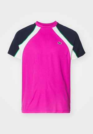 Camiseta atlética fucsia con mangas raglán en azul marino y blanco, que presenta un acento verde a lo largo de la costura del hombro y un pequeño logotipo en el pecho.