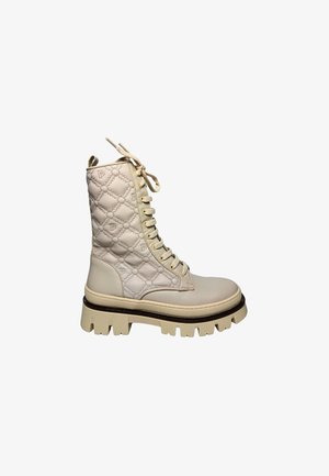Beige lace-up combat boot with quilted upper, chunky ridged sole, and small embossed letter patterns on the fabric upper.