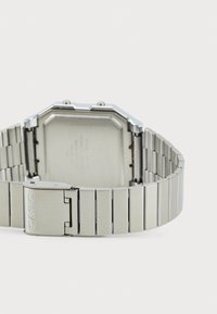 Montre en acier inoxydable argenté avec un boîtier octagonal, un bracelet métallisé et une boucle marquée "CASIO", mettant en valeur une texture lisse et un design élégant.
