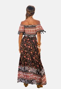 Maxi dress con design off-the-shoulder, in tessuto nero decorato con motivi floreali e orlo decorativo con accenti rossi e bianchi.