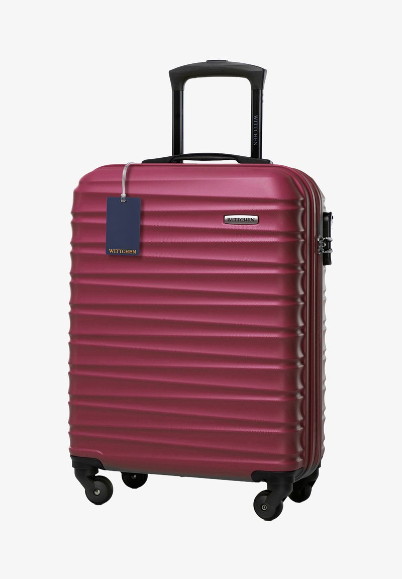 Valigia rigida di un profondo bordeaux con texture a righe orizzontali, manico retrattile e quattro ruote per una facile manovrabilità. Presenta un'etichetta con il marchio.