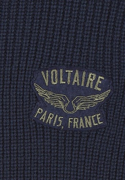 Navyblauwe gebreide stof met een textuurpatroon en een rechthoekig label, geperst met "VOLTAIRE" en "PARIJS, FRANKRIJK" in goud, versierd met vleugels.