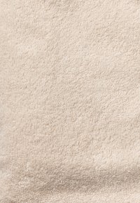 Beige handduk i mjukt bomullsfrotté med en behaglig, texturerad yta med ögliga fibrer, lämplig för suverän absorptionsförmåga och komfort.