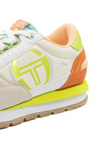 Der Sneaker verfügt über ein weißes synthetisches Obermaterial mit pastellfarbenen Akzenten in Orange, Grün und Blau, strukturiertem Wildleder und einem auffälligen Logo in fluorescentem Gelb.