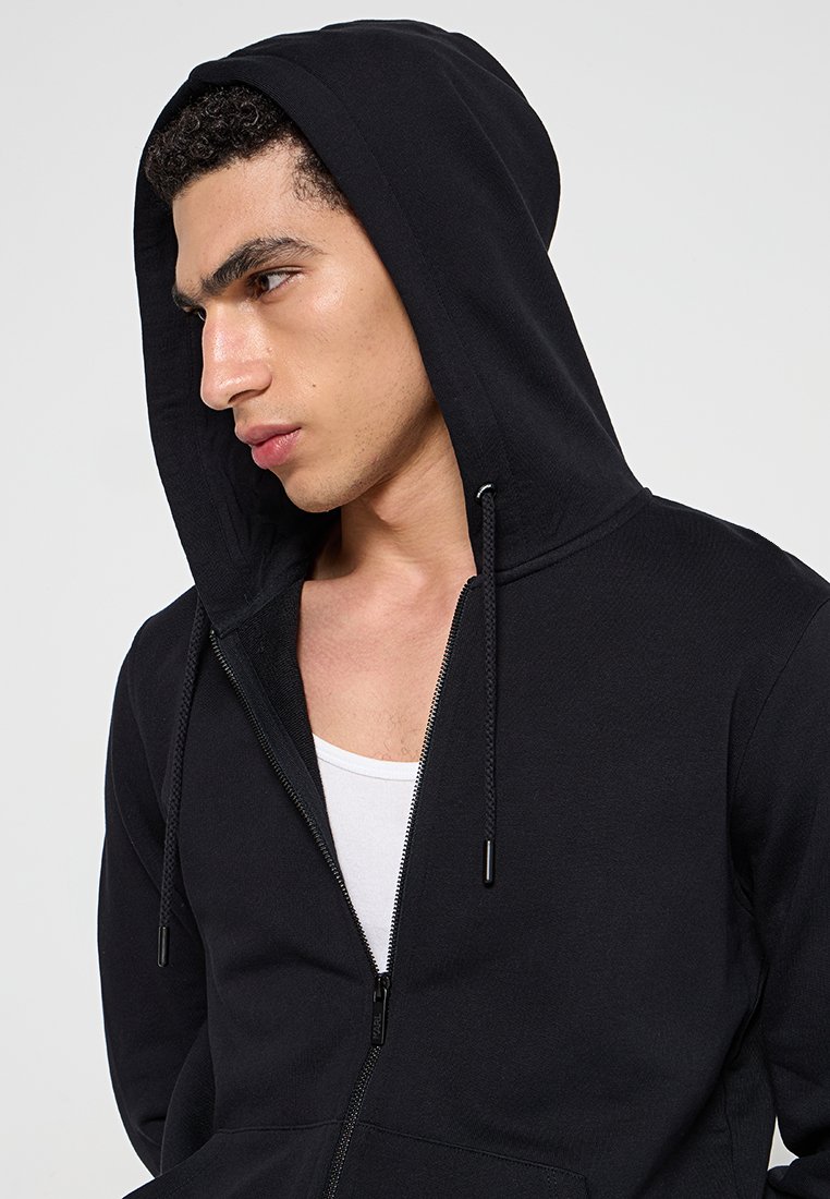 Felpa nera con zip completa, cappuccio con coulisse e polsini a coste. Realizzata in tessuto morbido, con linee pulite e vestibilità comoda.