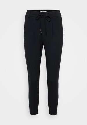 Zwarte taps toelopende broek van rekbaar materiaal, met een trekkoord in de taille, twee voorplooien en een zachte textuur.