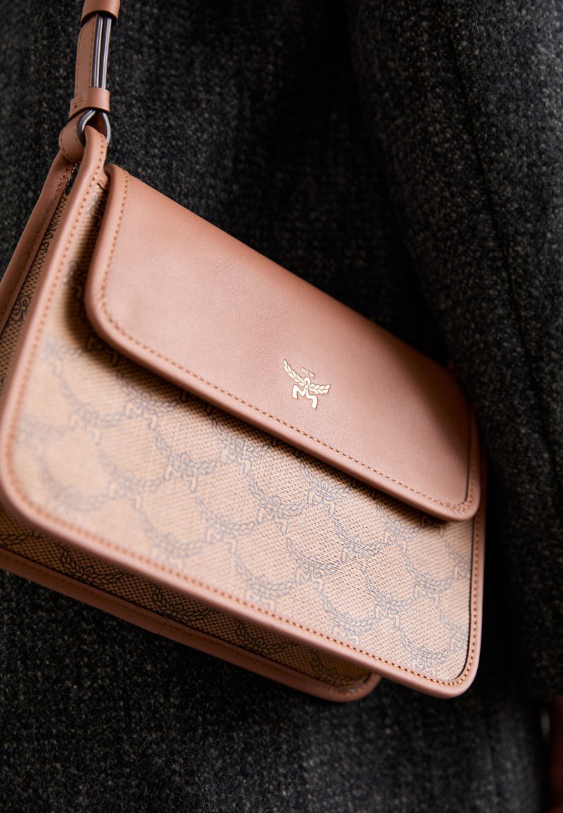 Καφέ δερμάτινη τσάντα crossbody με μοτίβο στο μπροστινό μέρος και χρυσή λογότυπο, με κλείσιμο καπάκι και ρυθμιζόμενο λουρί.