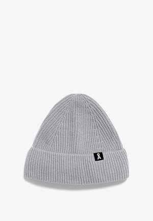 Hellgraue Strickmütze mit umgeschlagenem Bündchen, die ein kleines schwarzes rechteckiges Patch mit einem weißen symbolischen Logo zeigt.