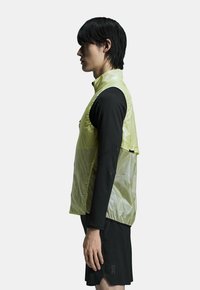 Let база, gennemsigtig gul l�øbevest med høj krave, parret med en sort langærmet skjorte og shorts, med et minimalistisk design.