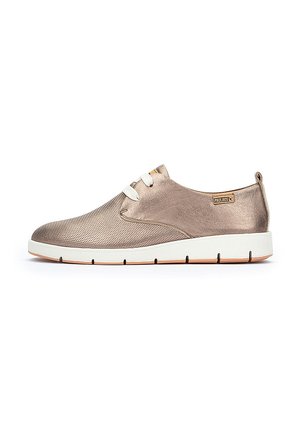 Baskets métalliques en bronze avec une tige en mesh texturé, lacets blancs et semelle en caoutchouc blanc avec des rainures rembourrées pour plus de flexibilité.