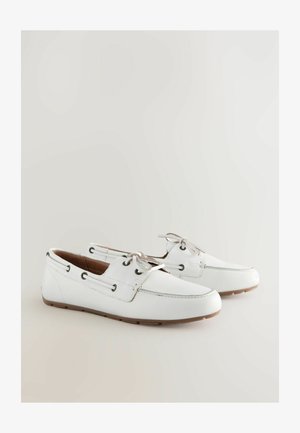 Bijele kožne brodske cipele s okruglim vrhom, vezanjem i kontrastnim tamnim okovom. Ravni gumeni đon s teksturiranim gripom.