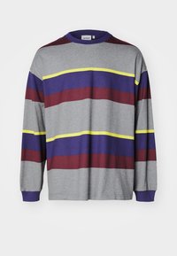 Garā piedurkņu pelēka krekla ar horizontālām svītrām vínogulājā, purpurā un dzeltenā krāsā. Apaļa kakla izgriezums un ribotas aproces. Gluda tekstūra.