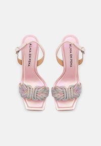 Růžové saténové sandály na vysokém podpatku s opleteným dělícím páskem posetým kamínky a čtveratou špičkou. Nastavitelný pásek kolem kotníku pro bezpečné upevnění.